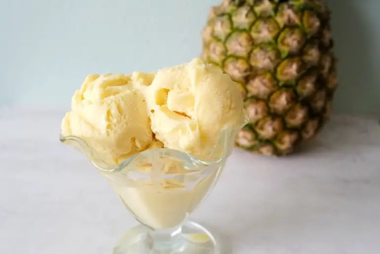 pineapple in a glass dish with a whole pineapple in the background