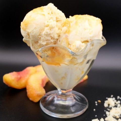 peach pie ice cream in a glass dish with a black background