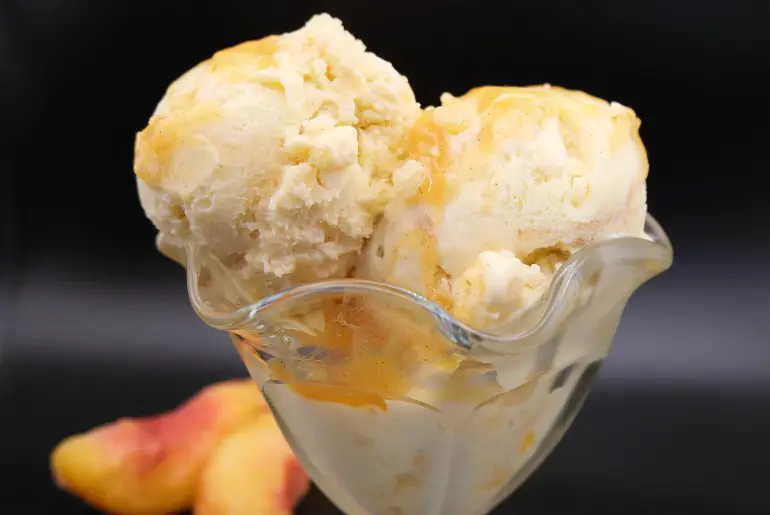 peach pie ice cream with black background and peaches in the background