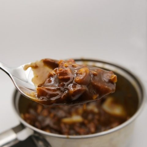 a spoonful of pecan caramel with the pan of caramel in the background