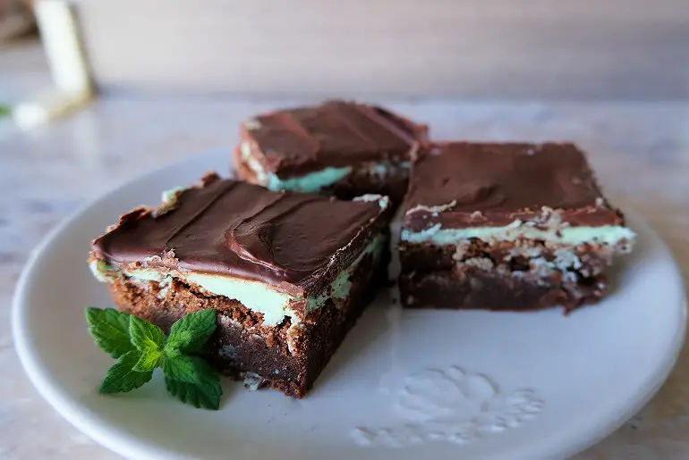 3 mint brownies arranged on a white plate and garnished with mint leaves