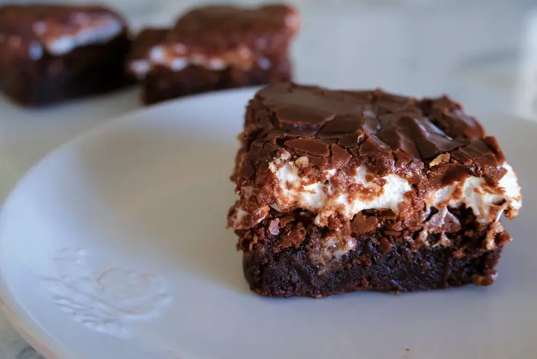 brownie on a white plate with 2 brownies in the background