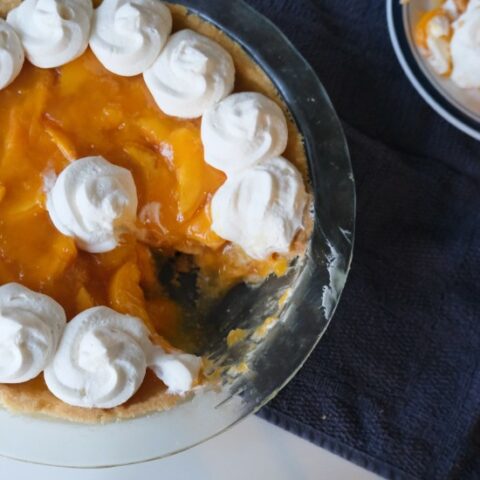 peach pie on a blue cloth with a slice removed