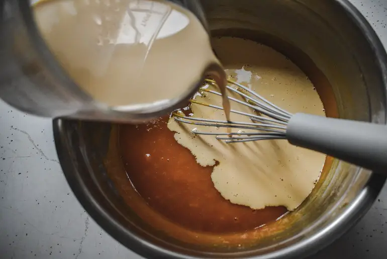 pumpkin puree in a bowl with evaporated milk being poured in