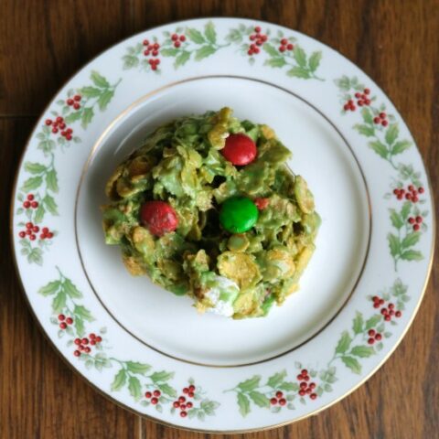 green cornflake m and m cookie on a plate with holly on the edges