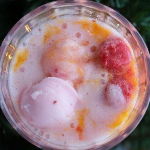 overhead shot of raspberries and sherbet in a glass of punch