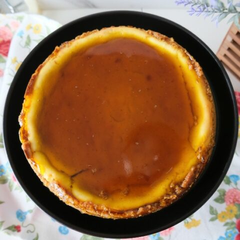 overhead shot of a cheesecake with a yellow gelee topping on a black plate